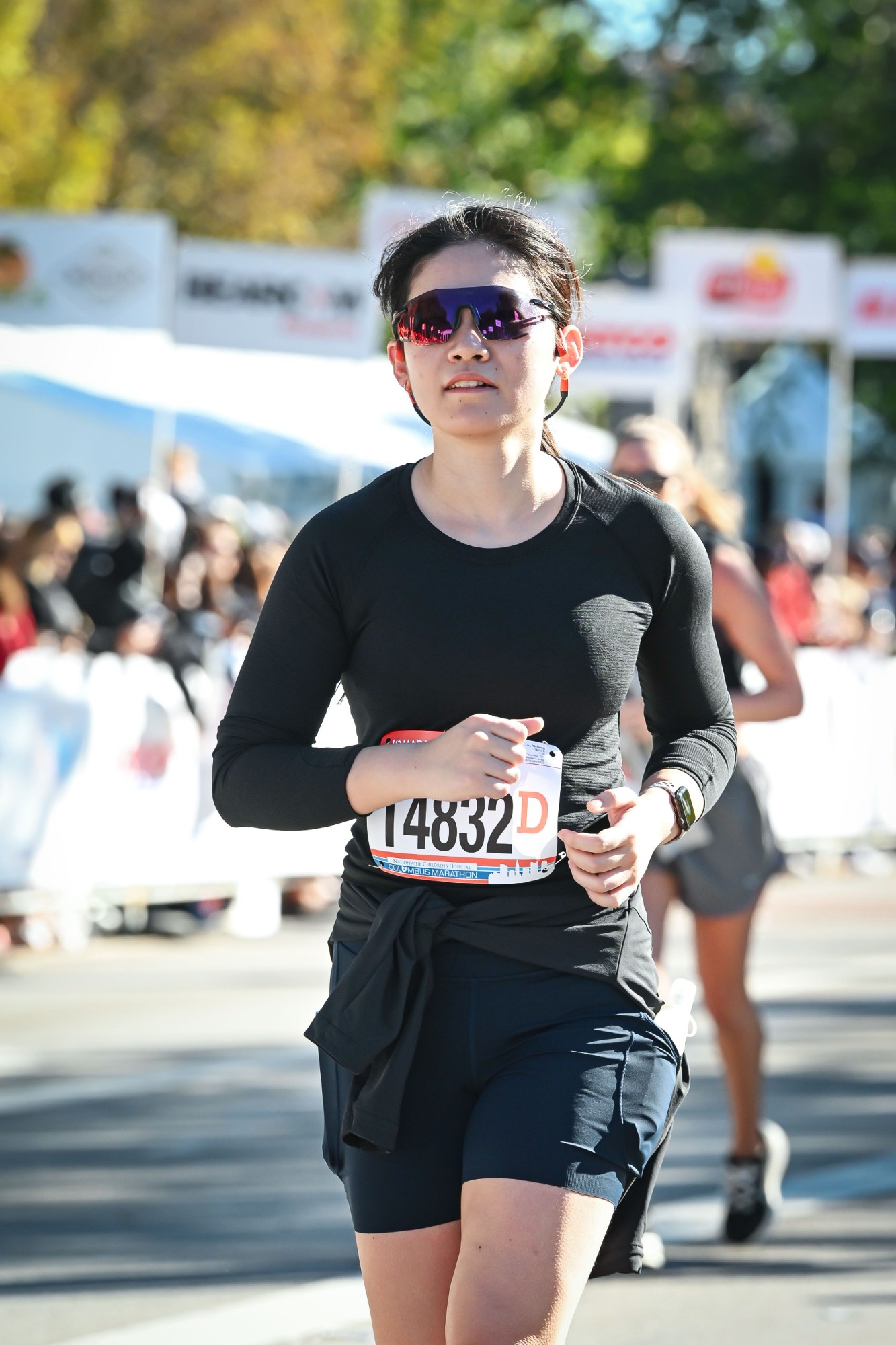 Yicheng Liu running the 2026 Columbus half marathon in sunglasses and a black long-sleeve top, wearing race bib 14832.